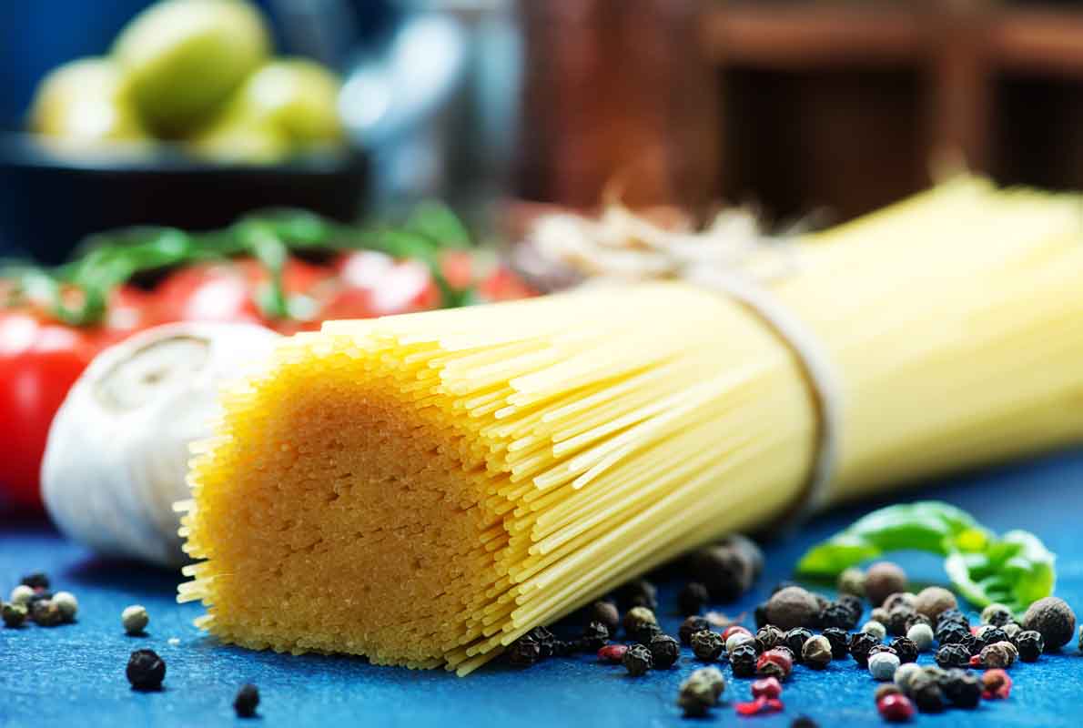 raw pasta with spice and raw tomato on a table